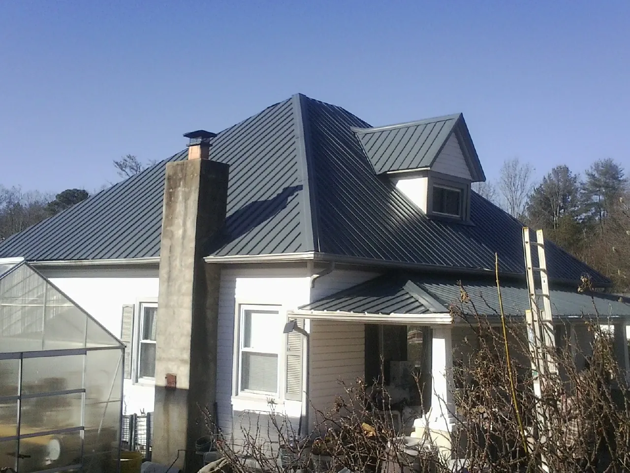 Dark blue standing seam metal roof on a white farmhouse with dormer — Slate & Tile Roof Repair by Roofing Brothers in New Riegel