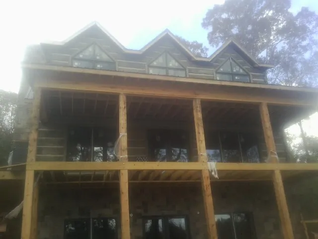 Dormers and porch framing on a large log home under construction — Roof Coating work by our crew in New Riegel