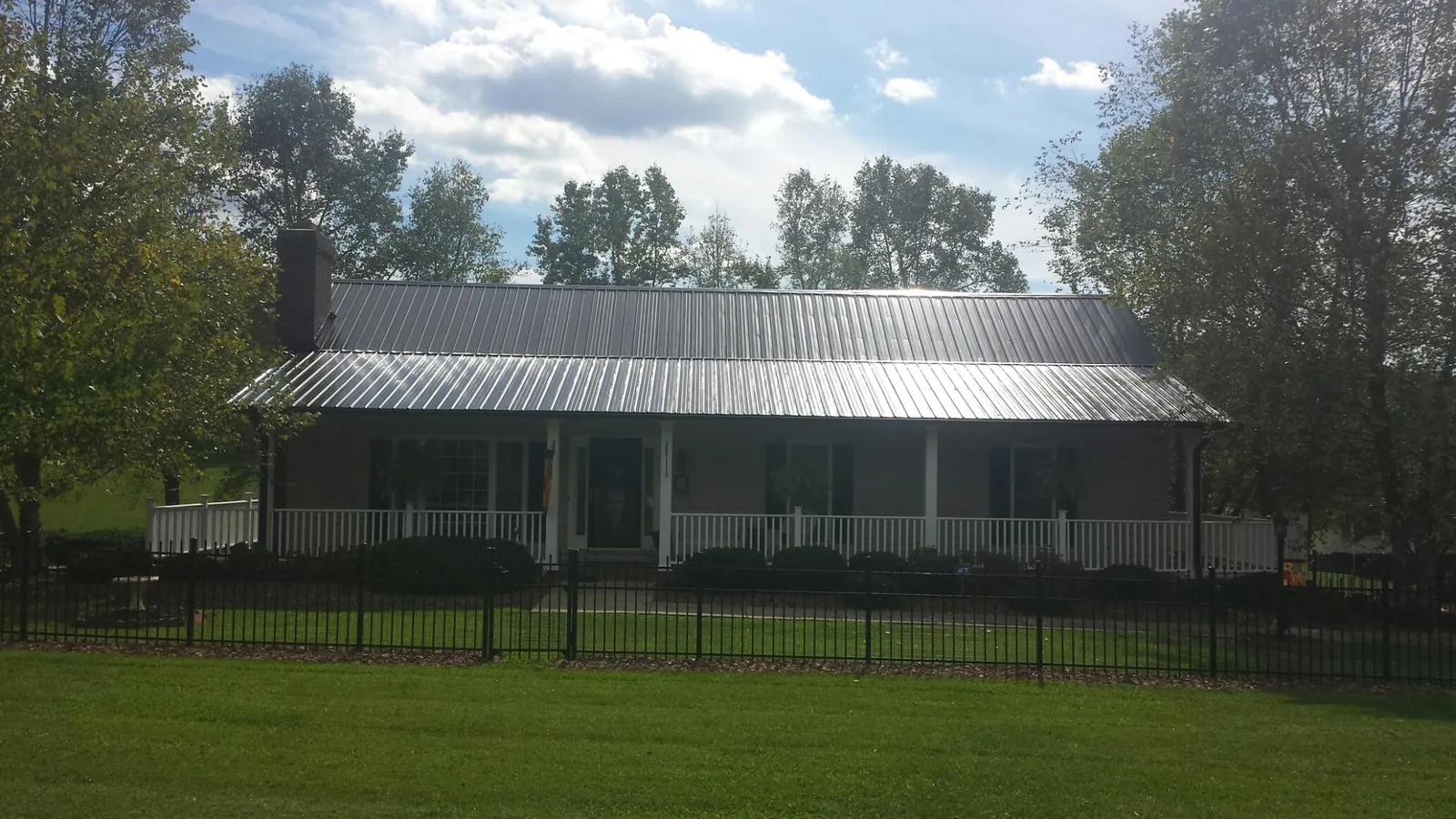 Gray metal roof on a brick ranch with a full width front porch — Gutter Guard Installation work by our crew in New Riegel