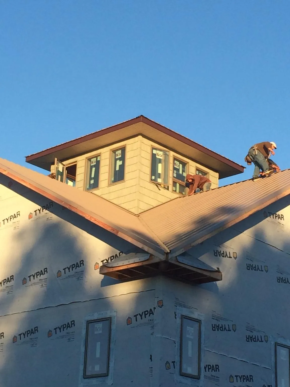 Roofers working around a rooftop cupola on a new metal roof at sunset — Roof Waterproofing in New Riegel by Roofing Brothers